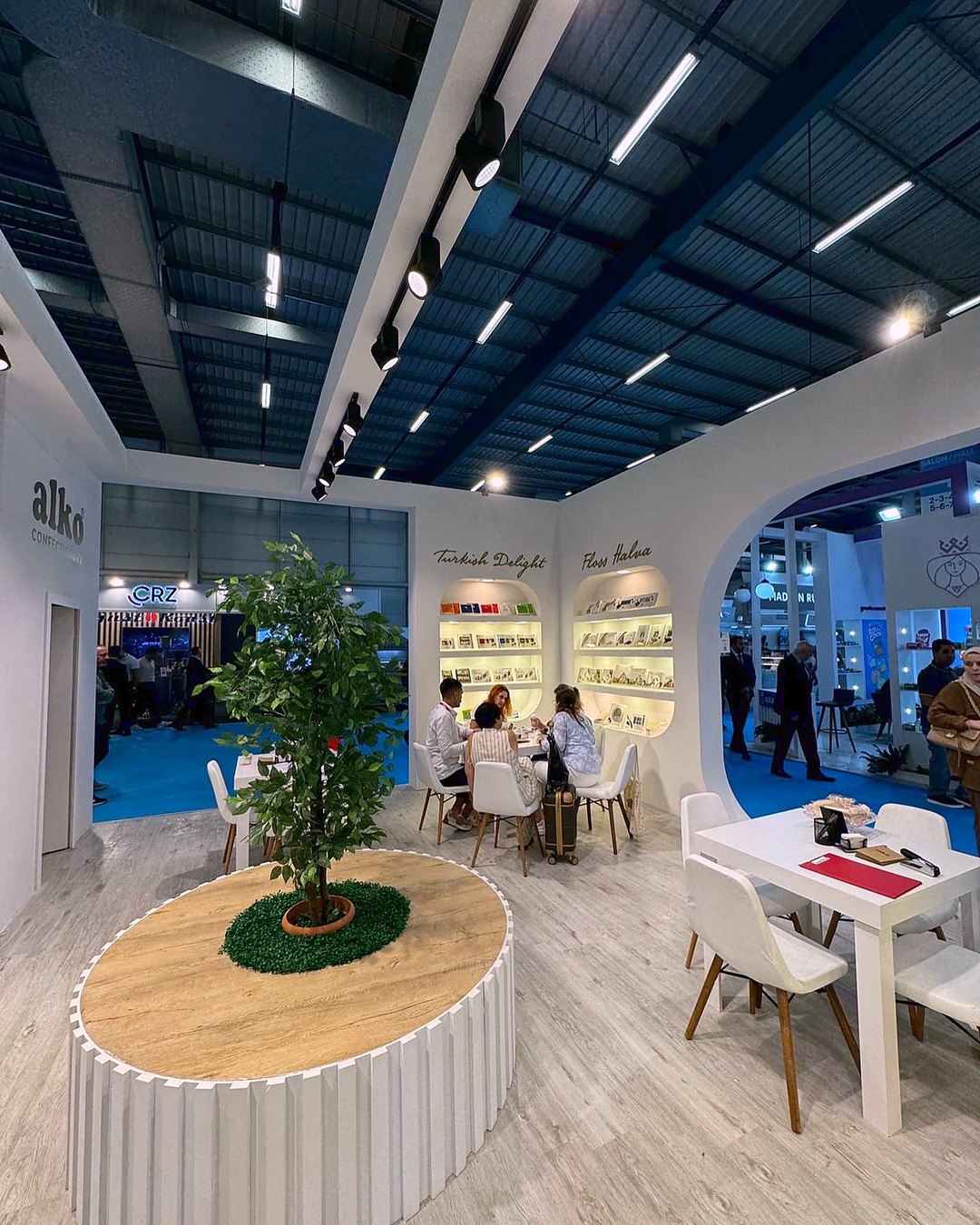 Stand d’exposition Alko au salon WorldFood Istanbul 2024 : Un portail courbe, un point végétal central et des zones d’accueil ouvertes relient découverte des produits et échanges