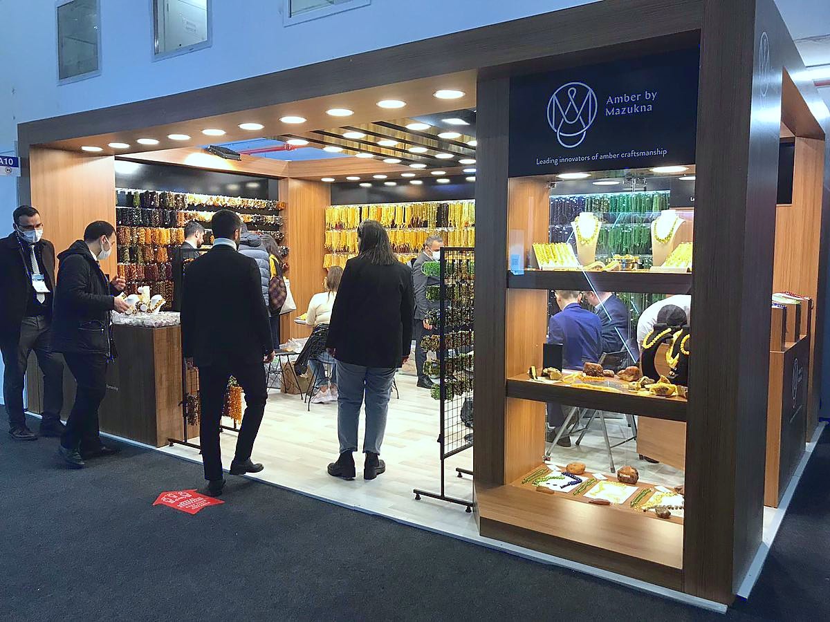 Stand d’exposition Amber by Mazukna au salon Istanbul Jewelry Show 2022 : Une palette noire et or, des vitrines éclairées et un accueil chaleureux composent un écrin mesuré pour la joaillerie