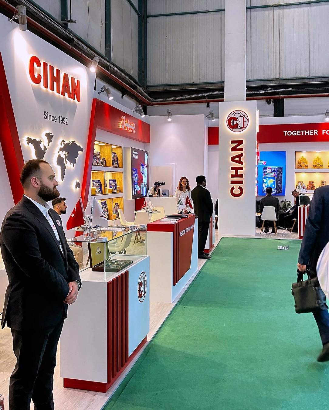 Stand d’exposition Cihan Food au salon WorldFood Istanbul 2023 : De hautes surfaces rouges, des rayonnages ordonnés et un espace de dégustation ouvert associent visibilité et circulation fluide