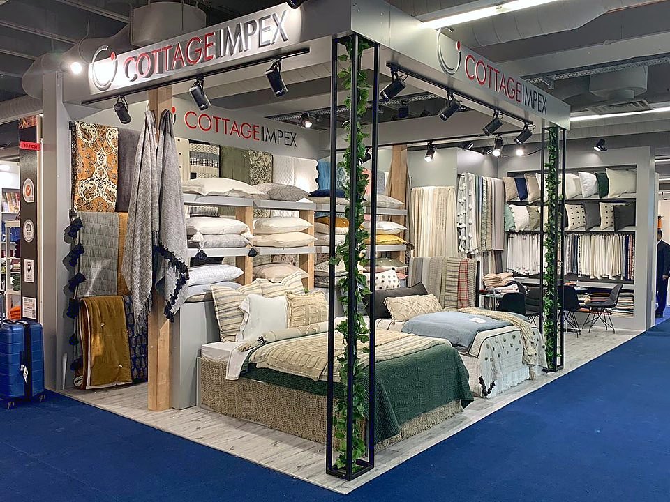 Stand d’exposition Cottage Impex au salon Heimtextil 2020 : Des scènes de chambre encadrées de noir transforment la collection textile en un parcours produit rythmé