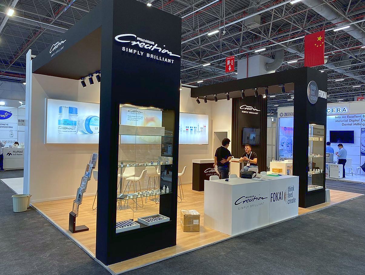 Stand d’exposition Fokai Dental au salon IDEX 2022 : Une haute tour noire, des étagères éclairées et un espace de réunion ouvert organisent clairement la présentation des produits dentaires