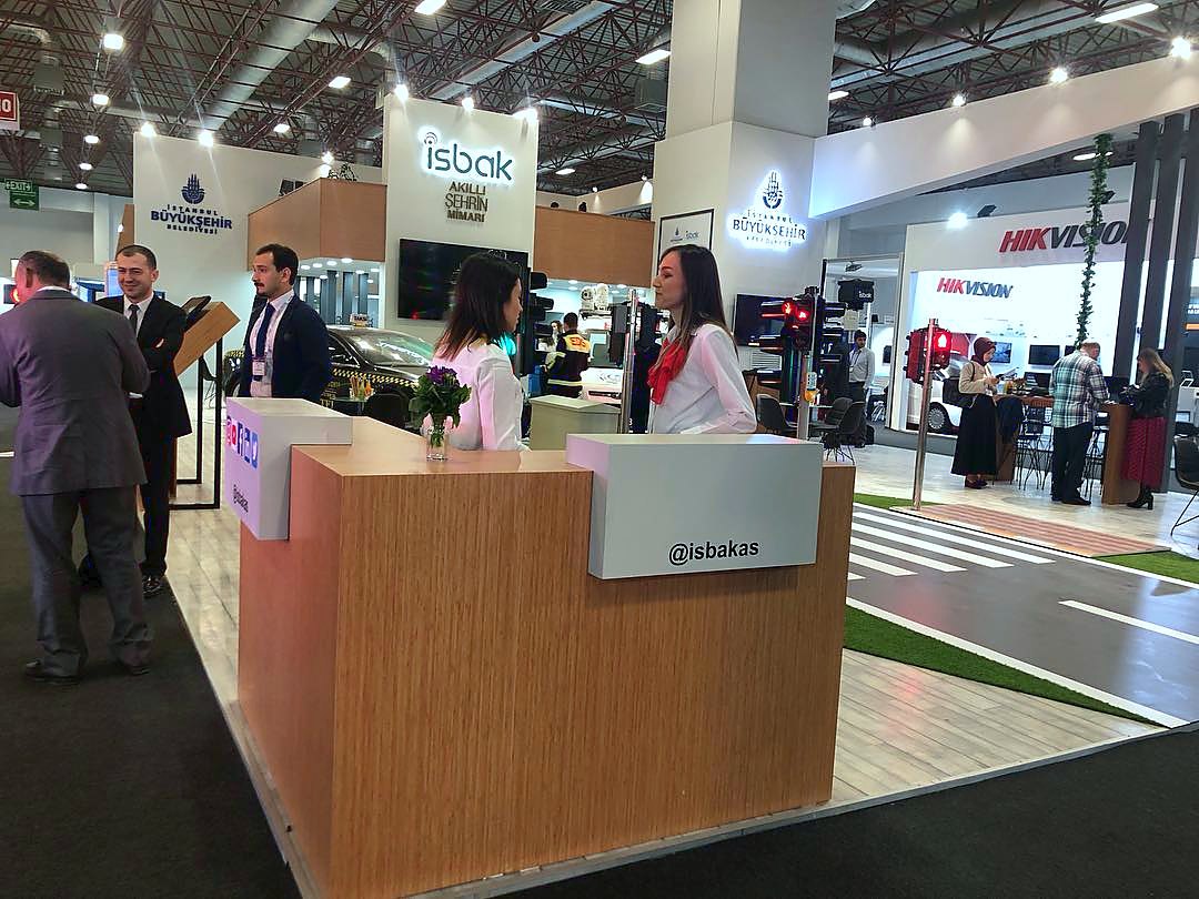 İSBAK exhibition stand at Intertraffic Istanbul 2019: A timber reception counter, geometric city graphics and open meeting space balance the technology story with a human spatial language