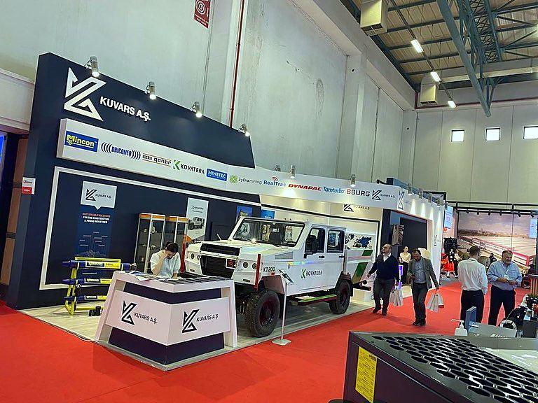 Kuvars / Kovatera exhibition stand at Maden Türkiye 2022: An exhibition environment that frames heavy equipment with clear brand blocks, long sightlines and generous visitor circulation