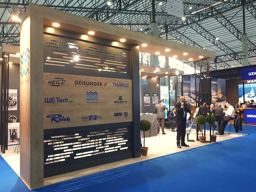 Stand d’exposition Marin İstanbul au salon Expomaritt Exposhipping 2019 : Un mur d’information noir, un contenu multimarque et un espace lounge organisent la présentation maritime autour des échanges