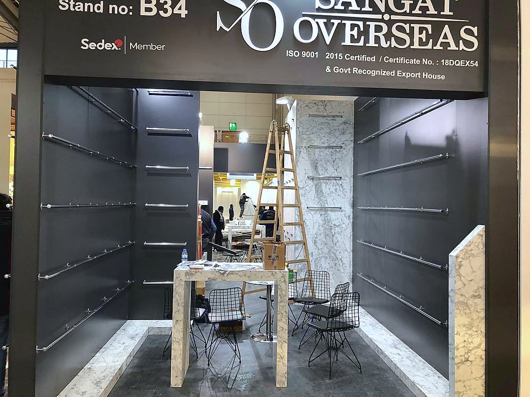 Stand d’exposition Sangat Overseas au salon DOMOTEX Hannover 2019 : Des surfaces anthracite et une présentation linéaire transforment les revêtements en un parcours continu de comparaison