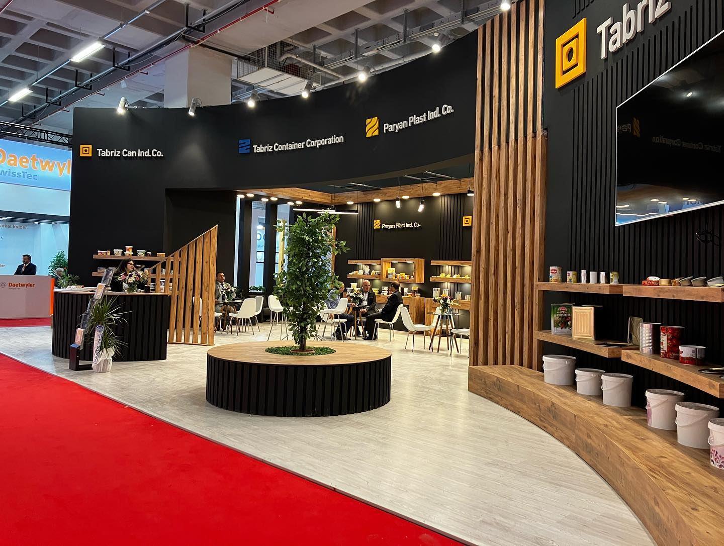 Tabriz Can exhibition stand at Avrasya Ambalaj 2022: A bold exhibition environment combining a black architectural frame, warm timber finishes and open product display