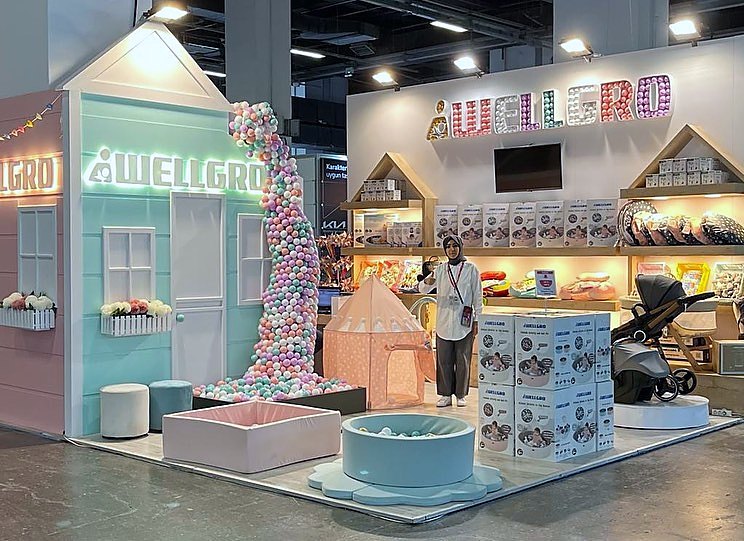Stand d’exposition Wellegro au salon IBS Anne Bebek Çocuk 2022 : Des façades pastel, des murs produits continus et des transitions douces présentent la collection mère-bébé avec clarté et légèreté